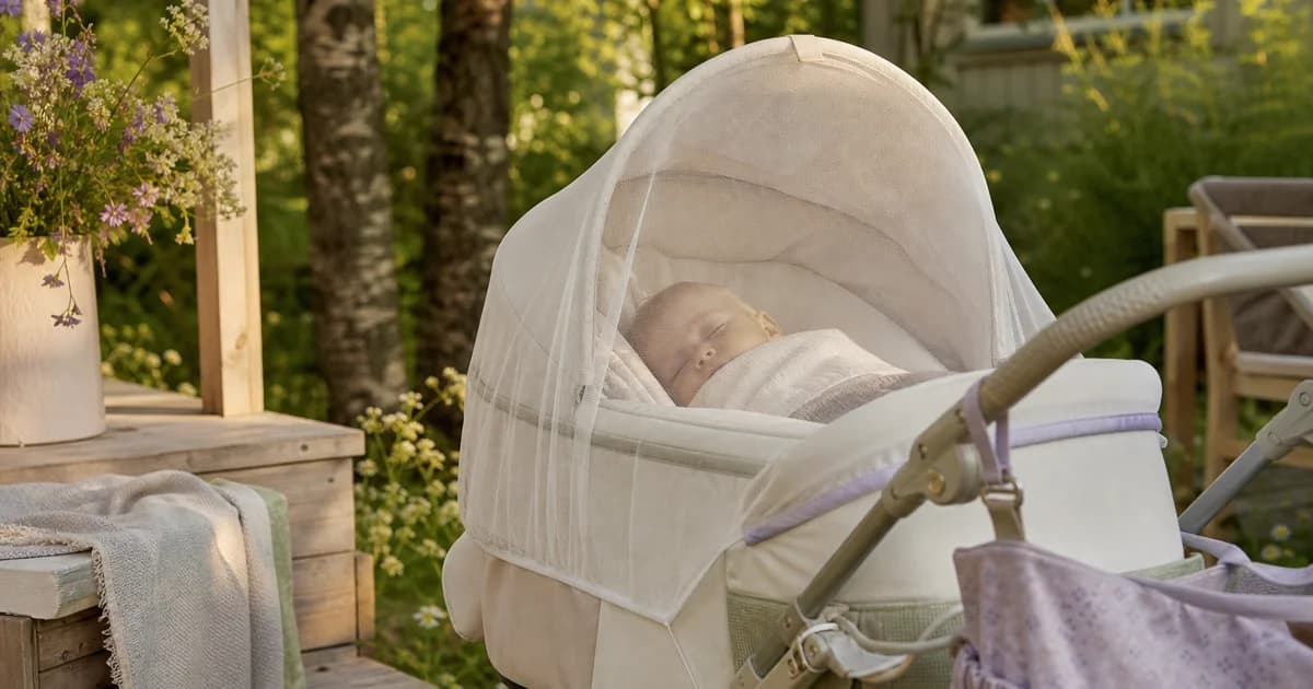 Baby ligger trygt i barnevogn med myggnett over i nordisk sommerhage