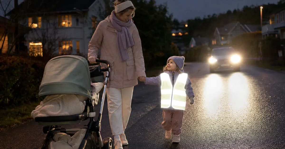 Barnevogn med reflekser som lyser opp i billykter på en mørk vei